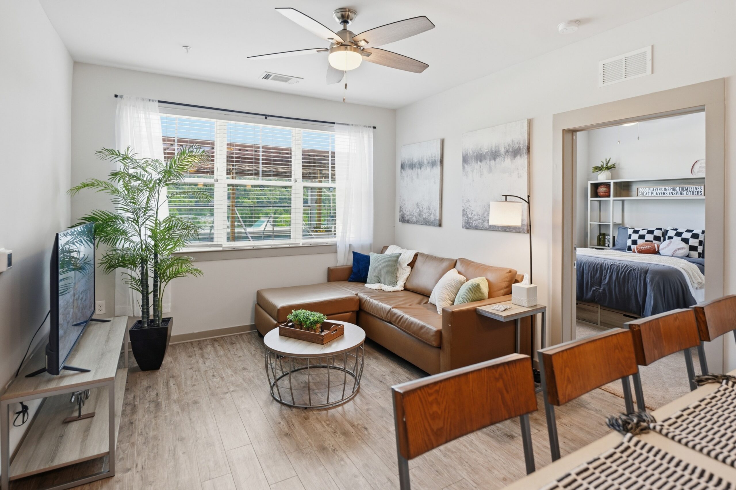 Living room with a ceiling fan and wood style plank flooring at The Finmore at 241 scaled